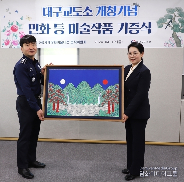 Myeongji University Professor Lee Mi-hyoung (right) donates a work of art to Daegu Prison Warden Han Tae-hwan.
