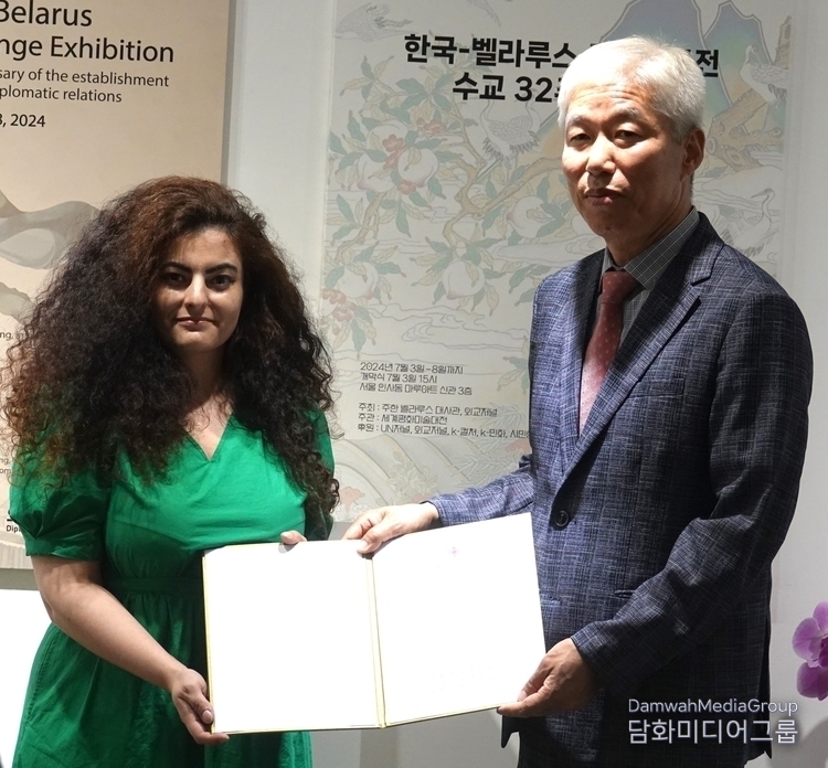 Chairman Lee Jon-young of Diplomacy Journal (right) delivers a scholarship to Kanzo Aryna, a Belarusian student studying folk painting at Myongji University.