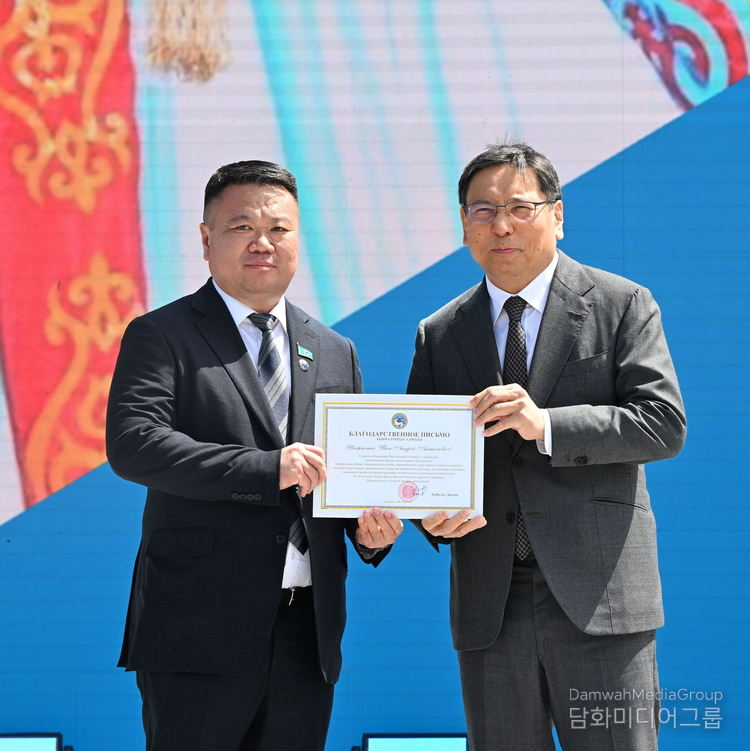 Andrey Shin (left) is receiving a Letter of appreciation from the mayor of Almaty Erbolat Dosayev